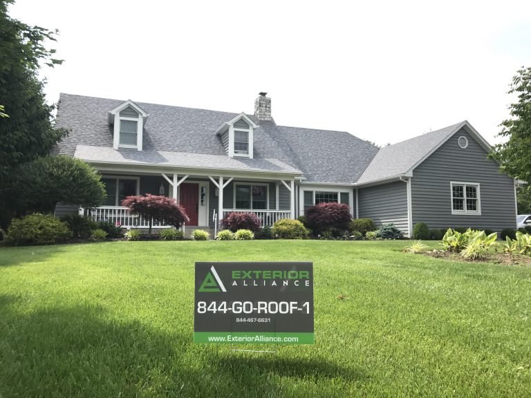 A charming suburban house with a well-maintained lawn and landscaping, featuring the logo and contact information of Exterior Alliance.