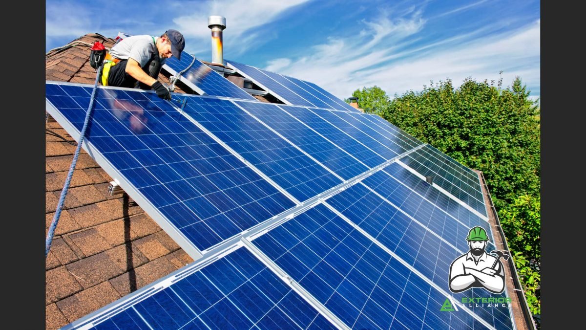 Two workers are installing solar panels on the roof of a house on a sunny day.
