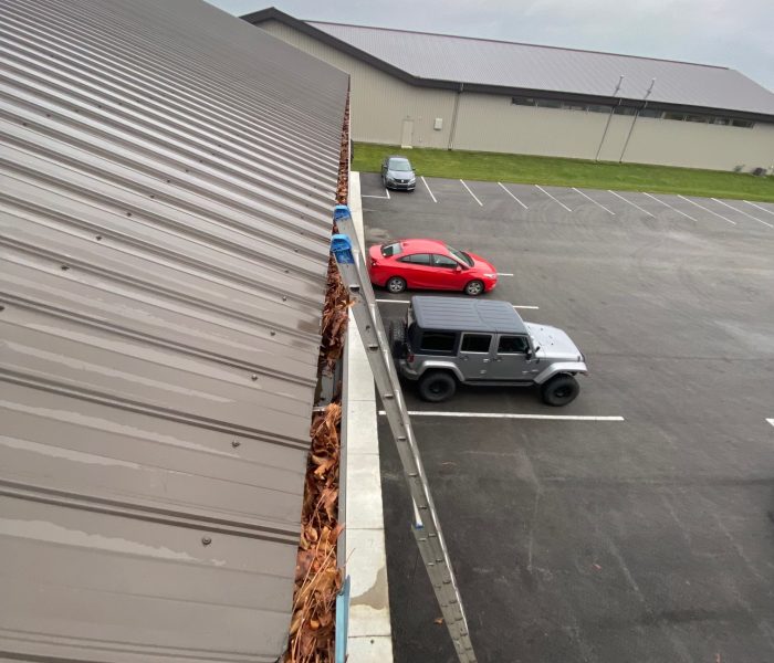 An elevated view of a parking lot with a few cars and fallen leaves near a building's rooftop edge for Gutter instillation Dublin